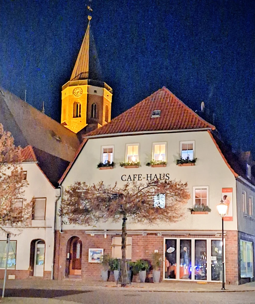Café-Haus Wagner am Abend mit Blick auf die beleuchtete Stadtkirche Calau